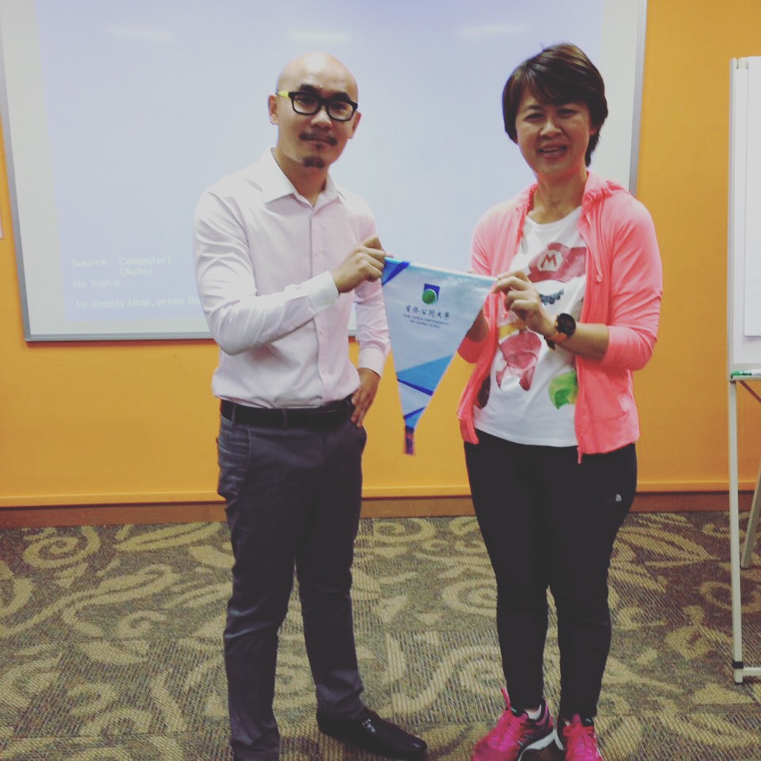 Rick Chan receiving a commemorative pennant from a representative of The Open University of Hong Kong