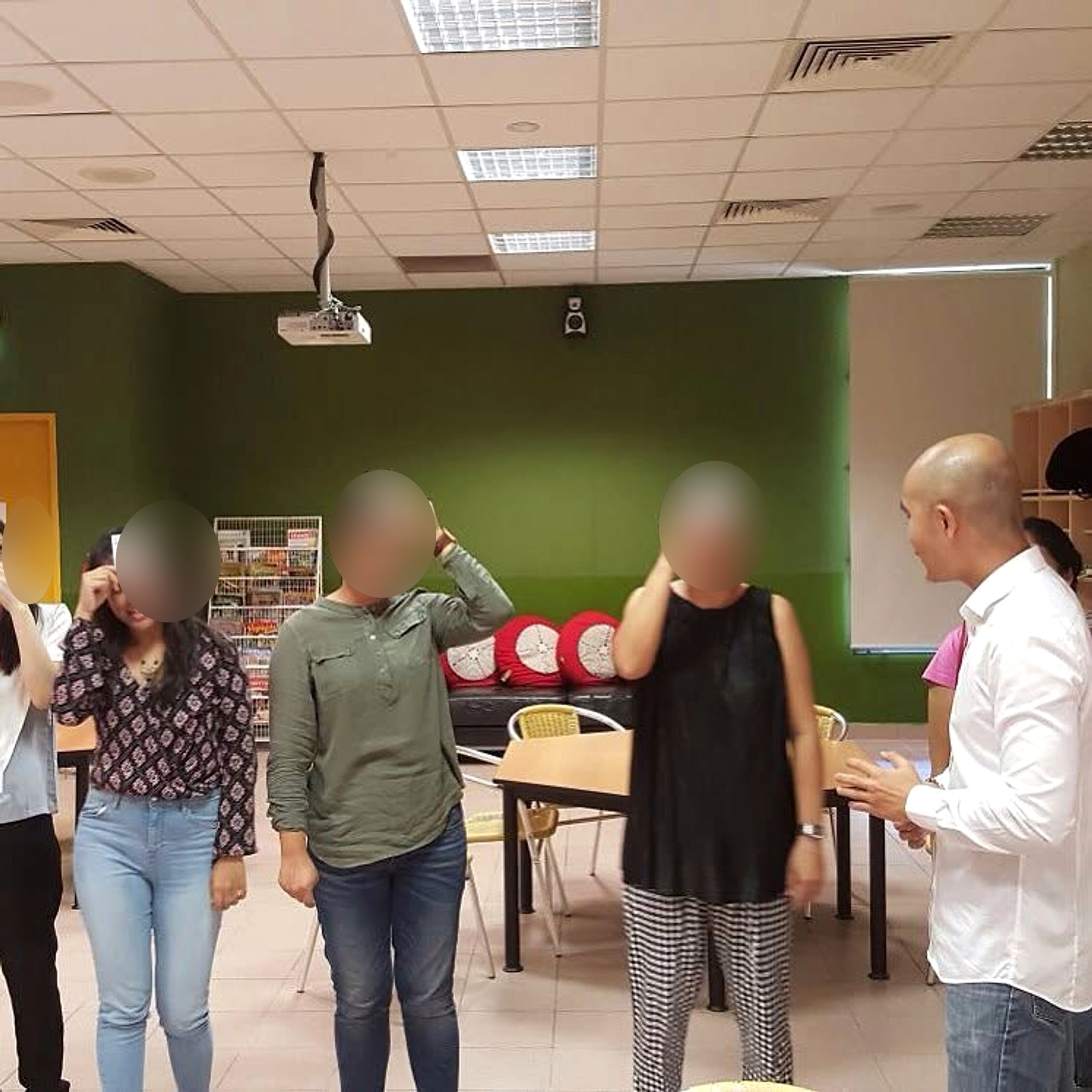 Chan guiding adult participants through an experiential learning activity, with participant faces obscured for privacy